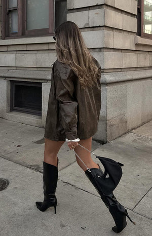 Faux leather oversized brown bomber jacket. Worn by model walking the street. 