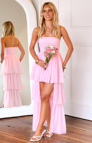 blonde model wearing a pink strapless dress with a high low skirt and tiered tulle outer