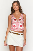 Girl wearing red and white print top and denim mini skirt holding cocktail glass.